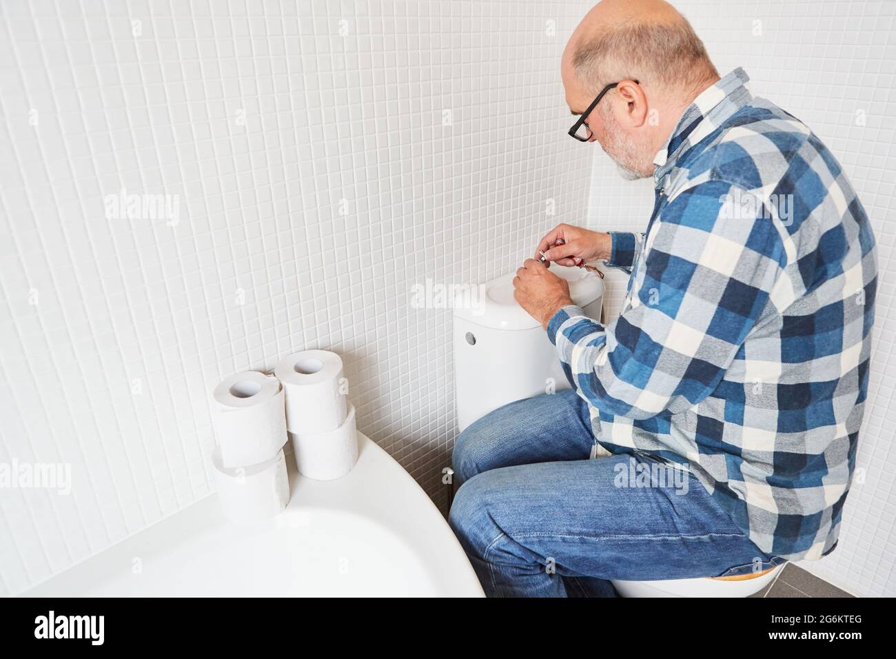 Plumber or do-it-yourselfer repairing the toilet flush on the toilet cistern Stock Photo