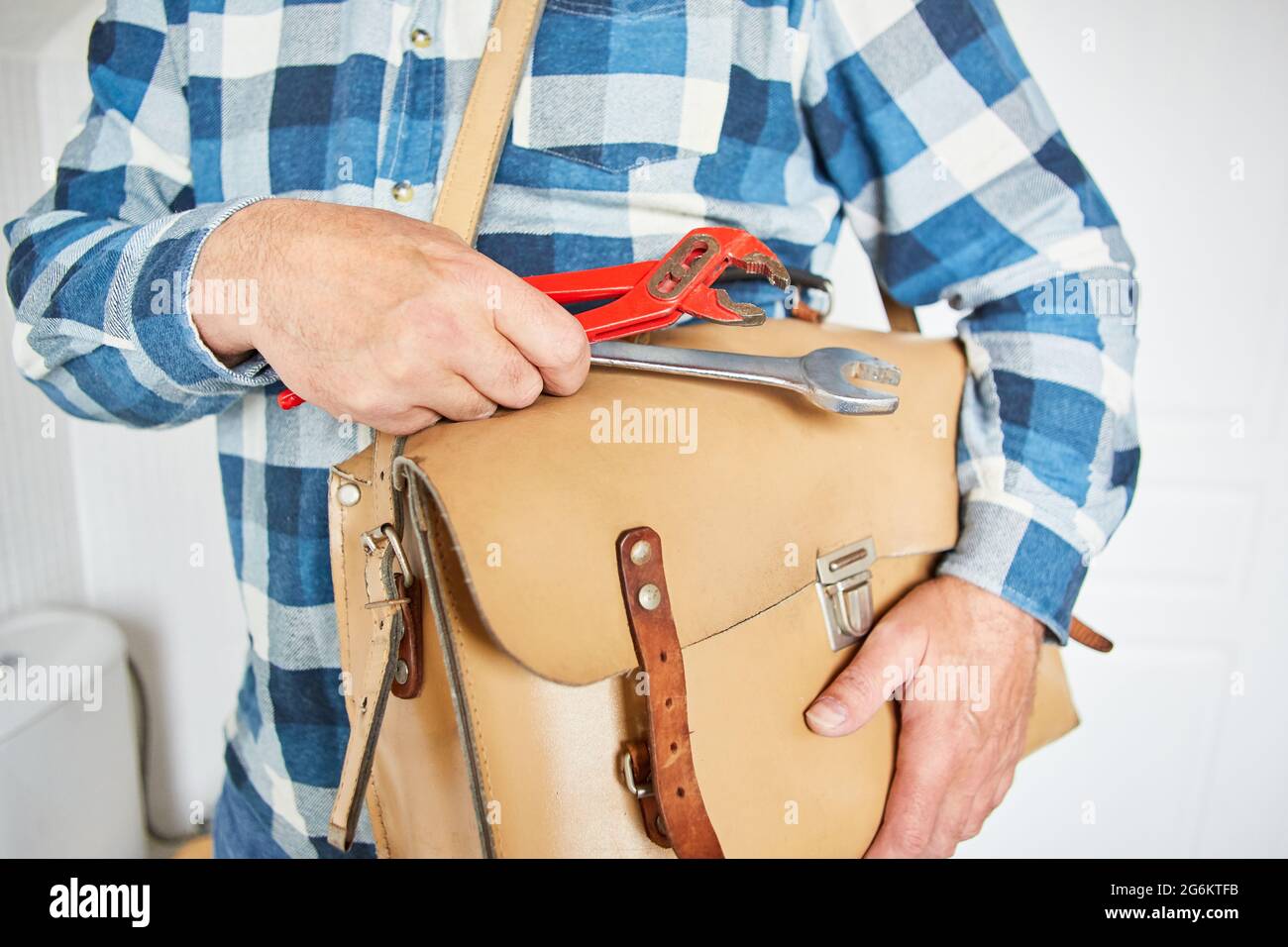 Craftsman as plumber from the emergency service with leather bag and tools Stock Photo