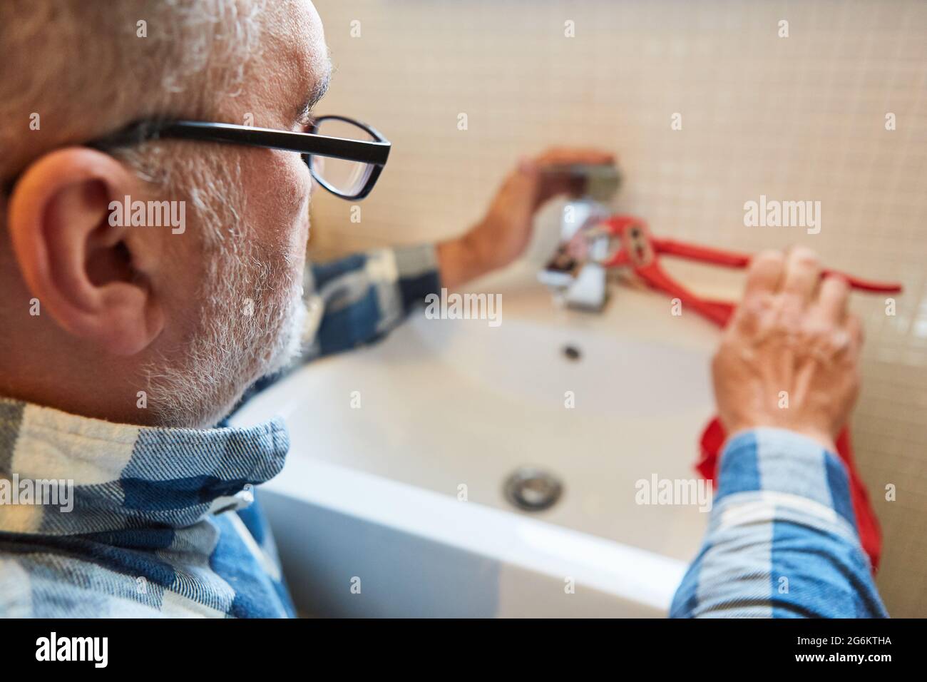 Craftsman plumber or handyman repairs broken faucet in bathroom Stock