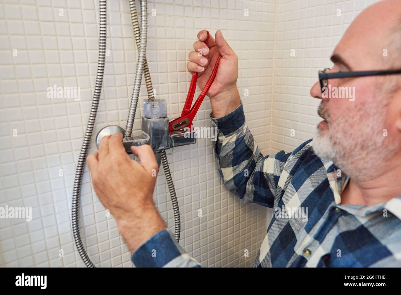 Handyman as a plumber with pipe wrenches assembles new shower hose in the shower Stock Photo Alamy