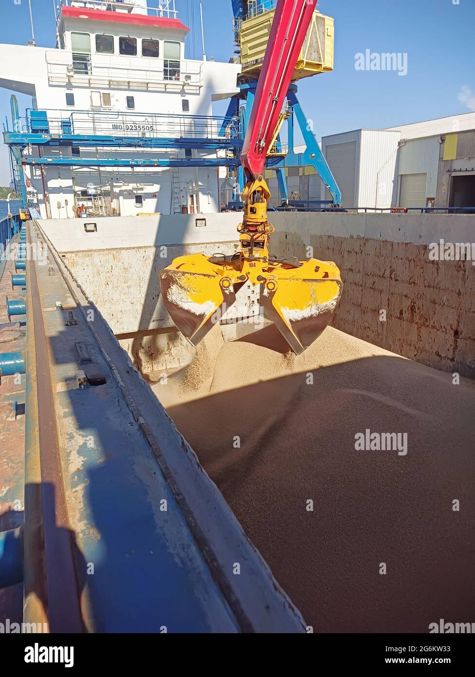 a crane with a manipulator bucket loads wheat onto a dry cargo ship in