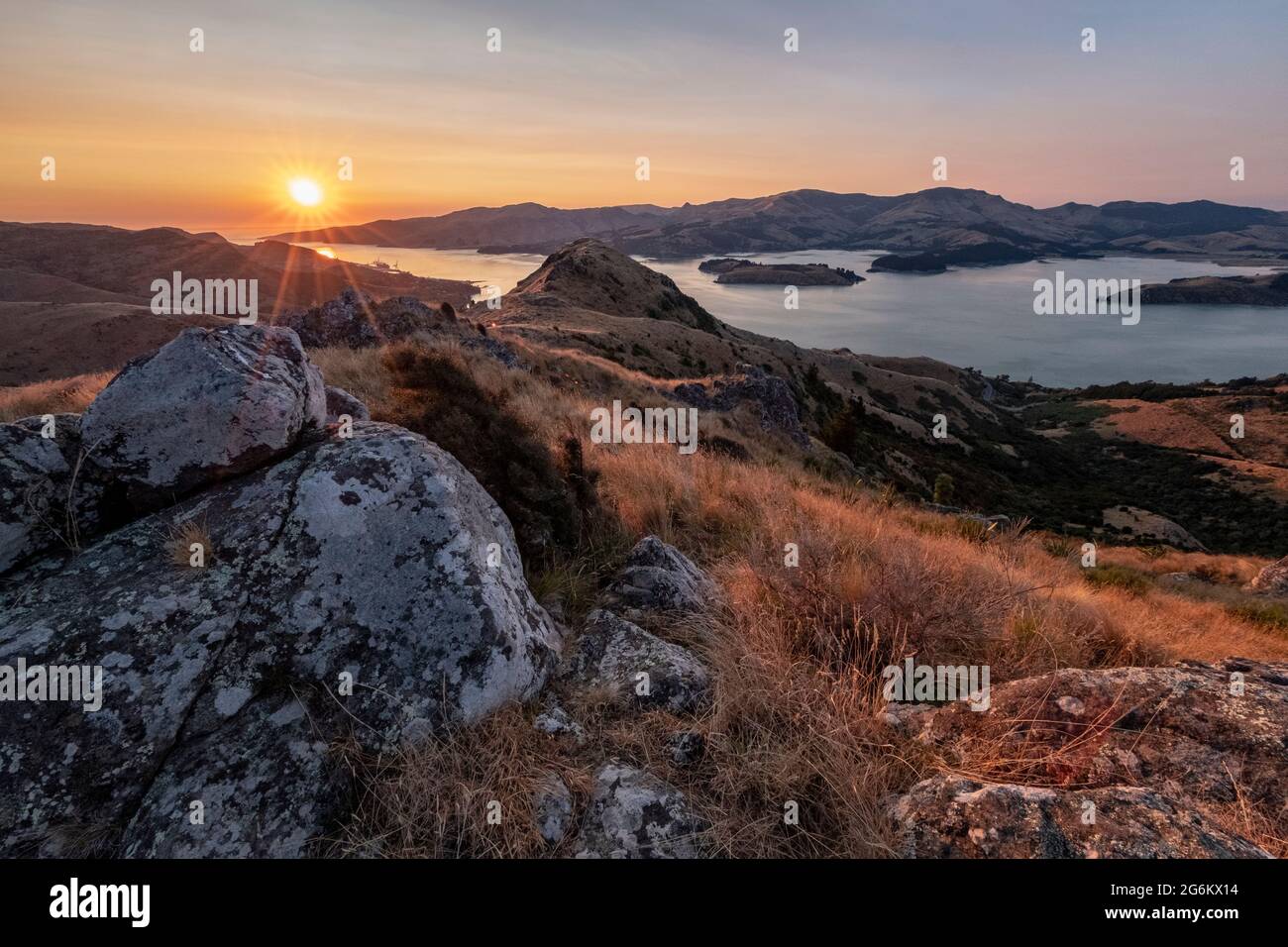 Sunrise over a rocky and grassy hill in the Porthills, Christchurch, Aotearoa New Zealand. Stock Photo