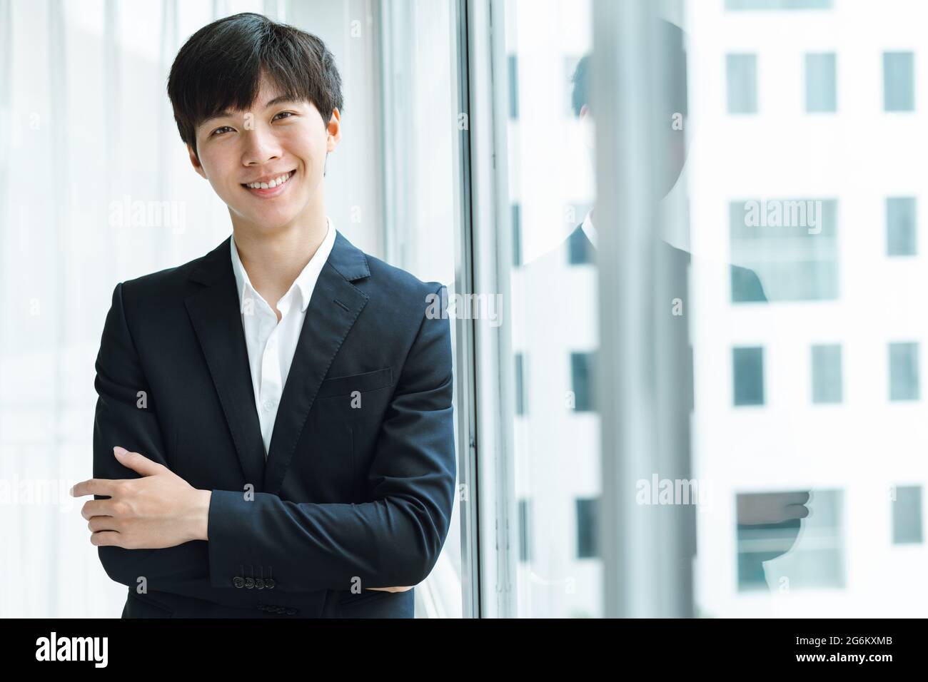 A man in a business suit confidently looks at the camera with his arms crossed Stock Photo