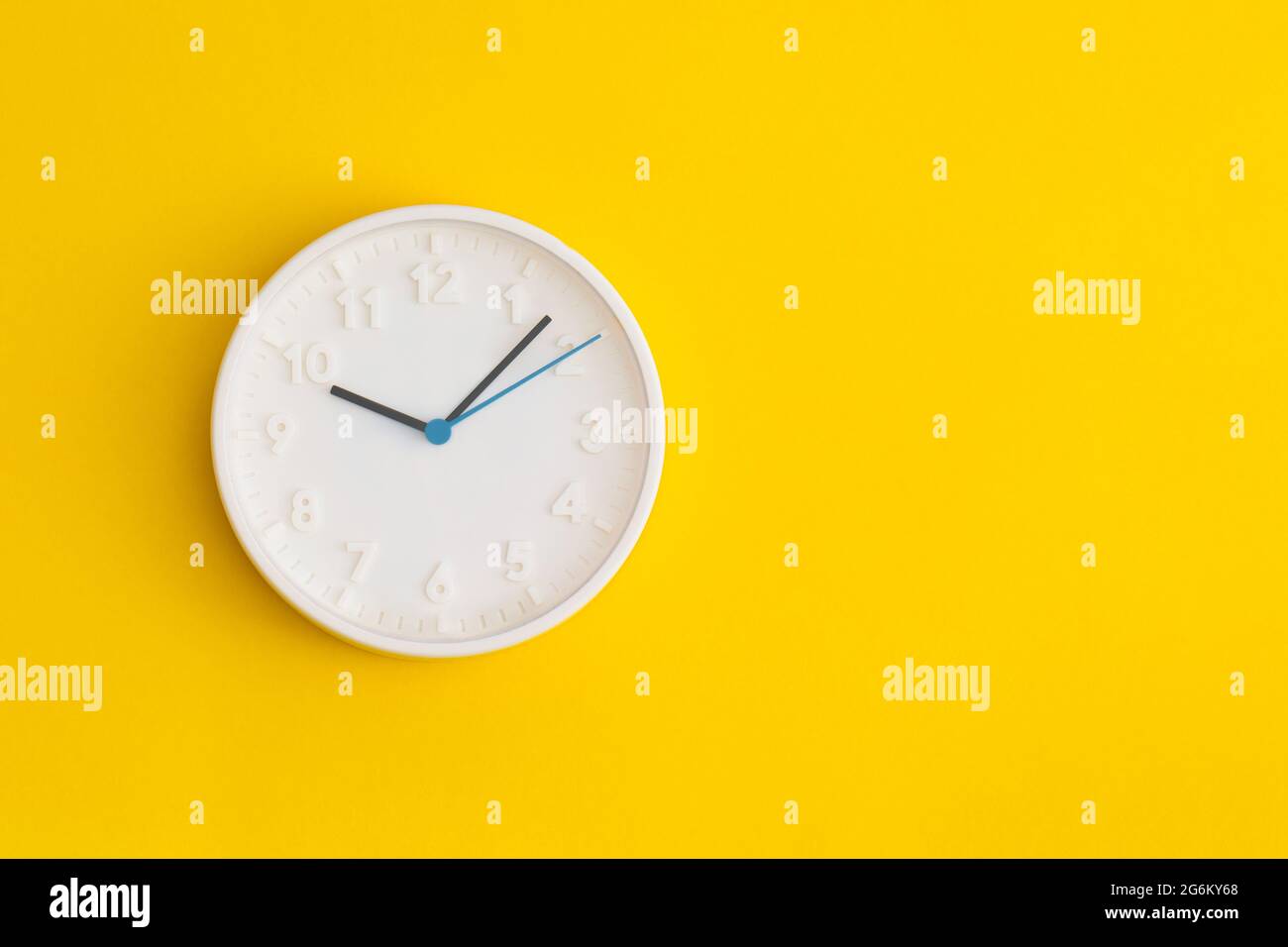 White wall Clock on yellow background. Stock Photo