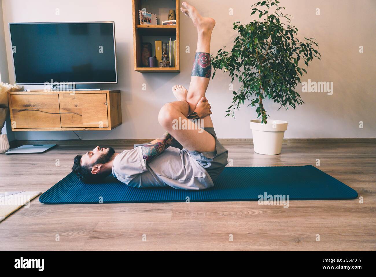 Side shot of Man doing yoga lying on mat with knees high Stock Photo