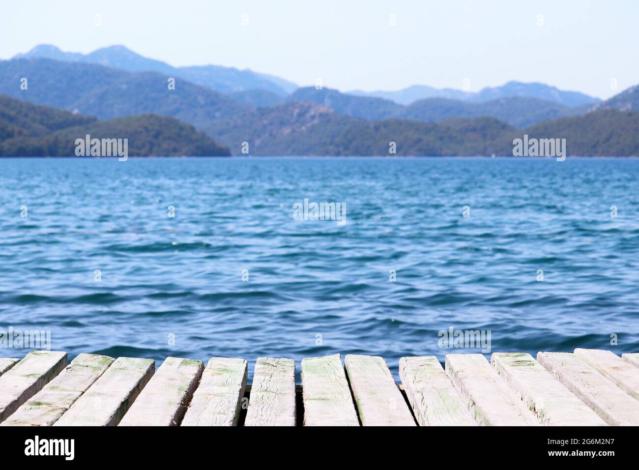 Beach vacation on the sea, background for summer vacation and travel. View from old wooden pier to deep blue water and misty mountains Stock Photo
