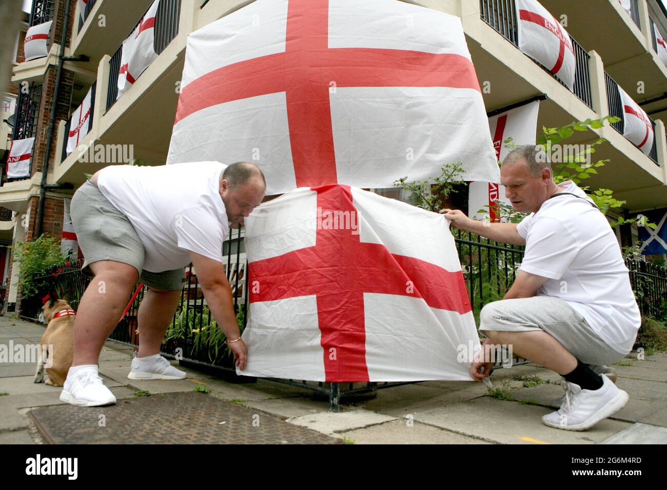 Chris Dowse (left) and Alan Putman, secure a flag on the Kirby Estate in Bermondsey, south London, where residents are showing their support for England ahead of their game against Denmark at Wembley on Wednesday evening in the second semi-final of Euro 2020. Picture date: Wednesday July 7, 2021. Stock Photo