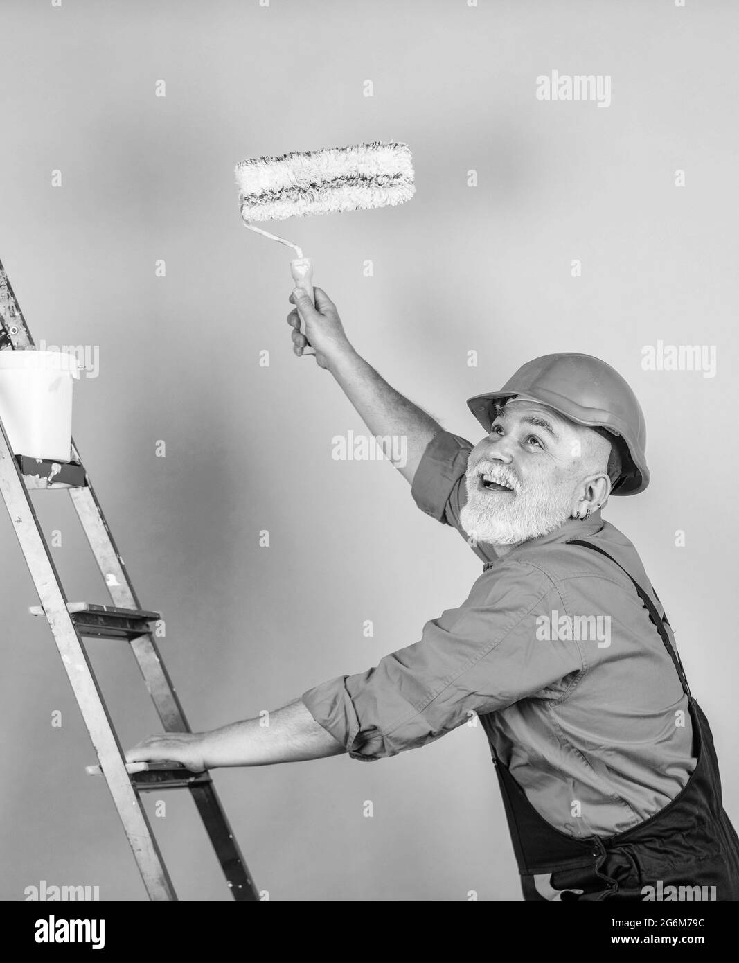 Repair concept. senior man painter use roller on ladder. painting the