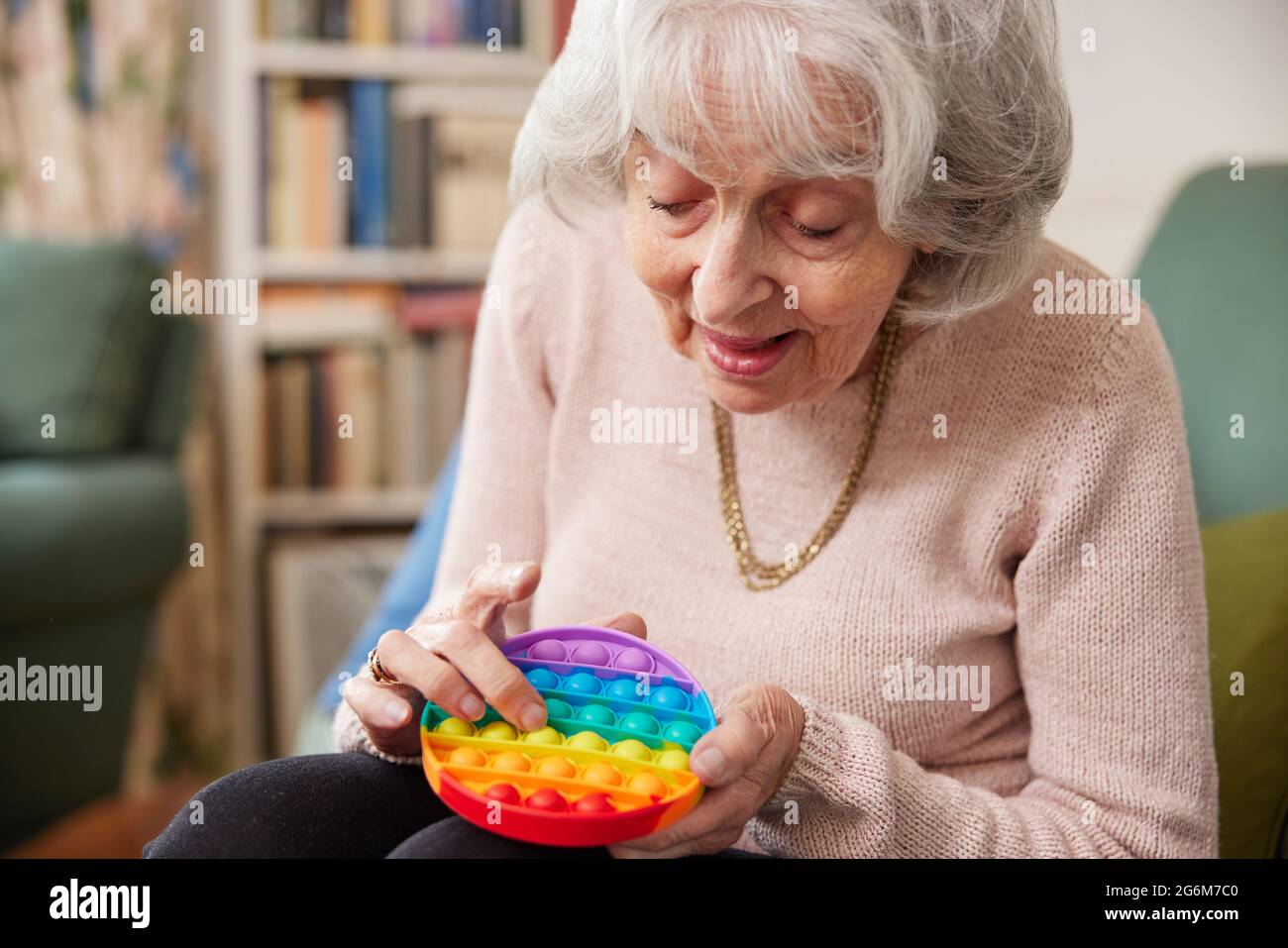 Senior Woman Using Colourful Fidget Toy To Improve Mental Stimulation At Home Stock Photo