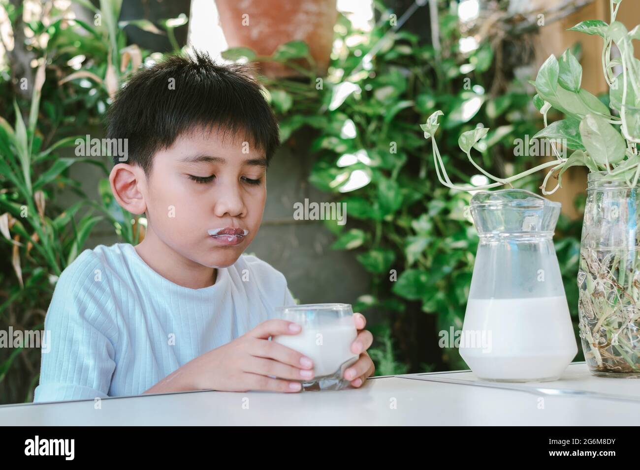 The boy's mouth was stained with milk stains after he drank the milk from the glass. Stock Photo