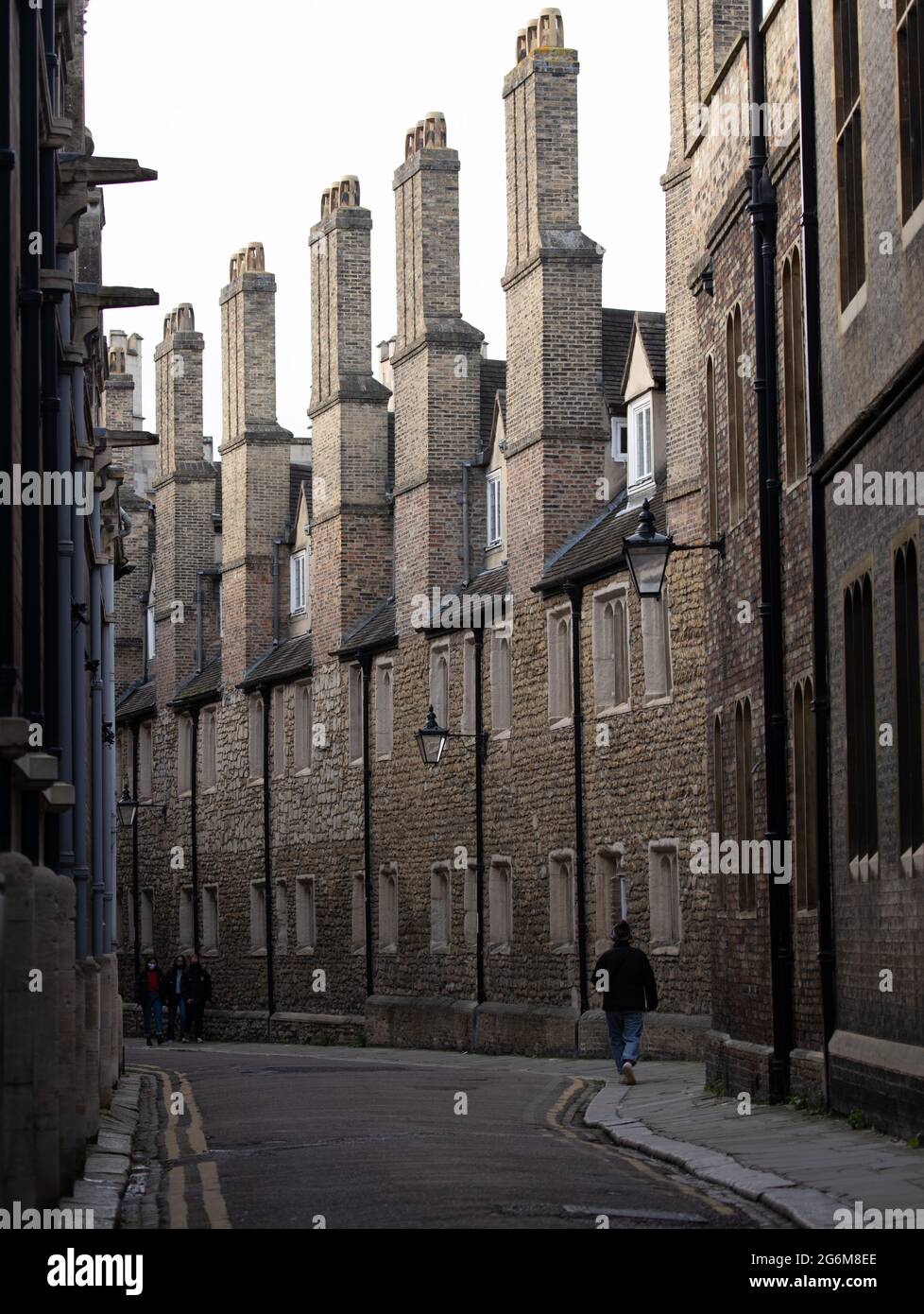 One person walking along the narrow lane lined old buildings with with tall Trinity college chimneys in Trinity Lane Cambridge England Stock Photo