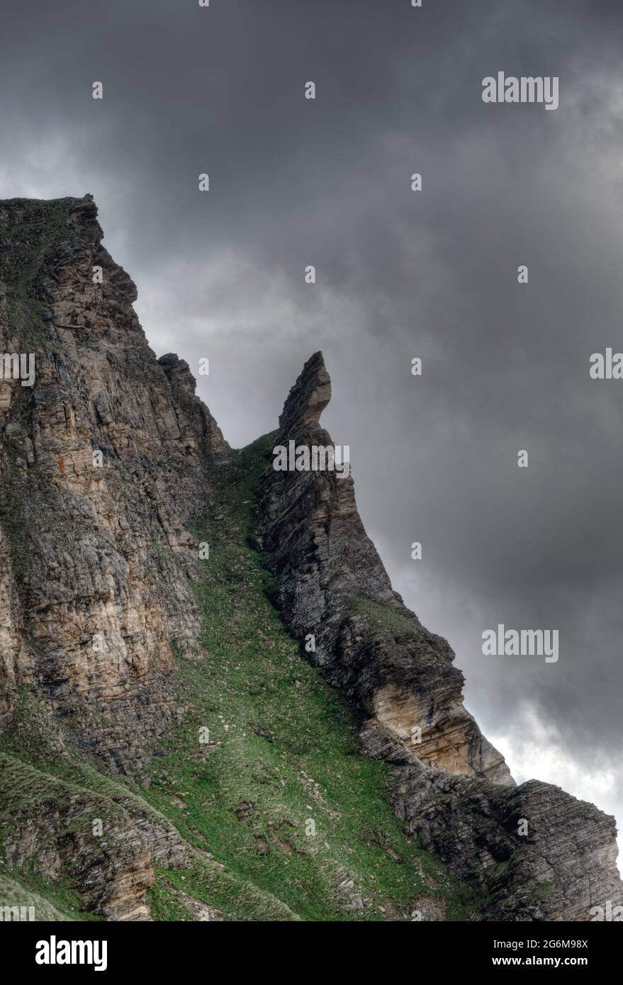 Capriciously shaped rock in mountains under threatening sky in the Italian Alps Stock Photo