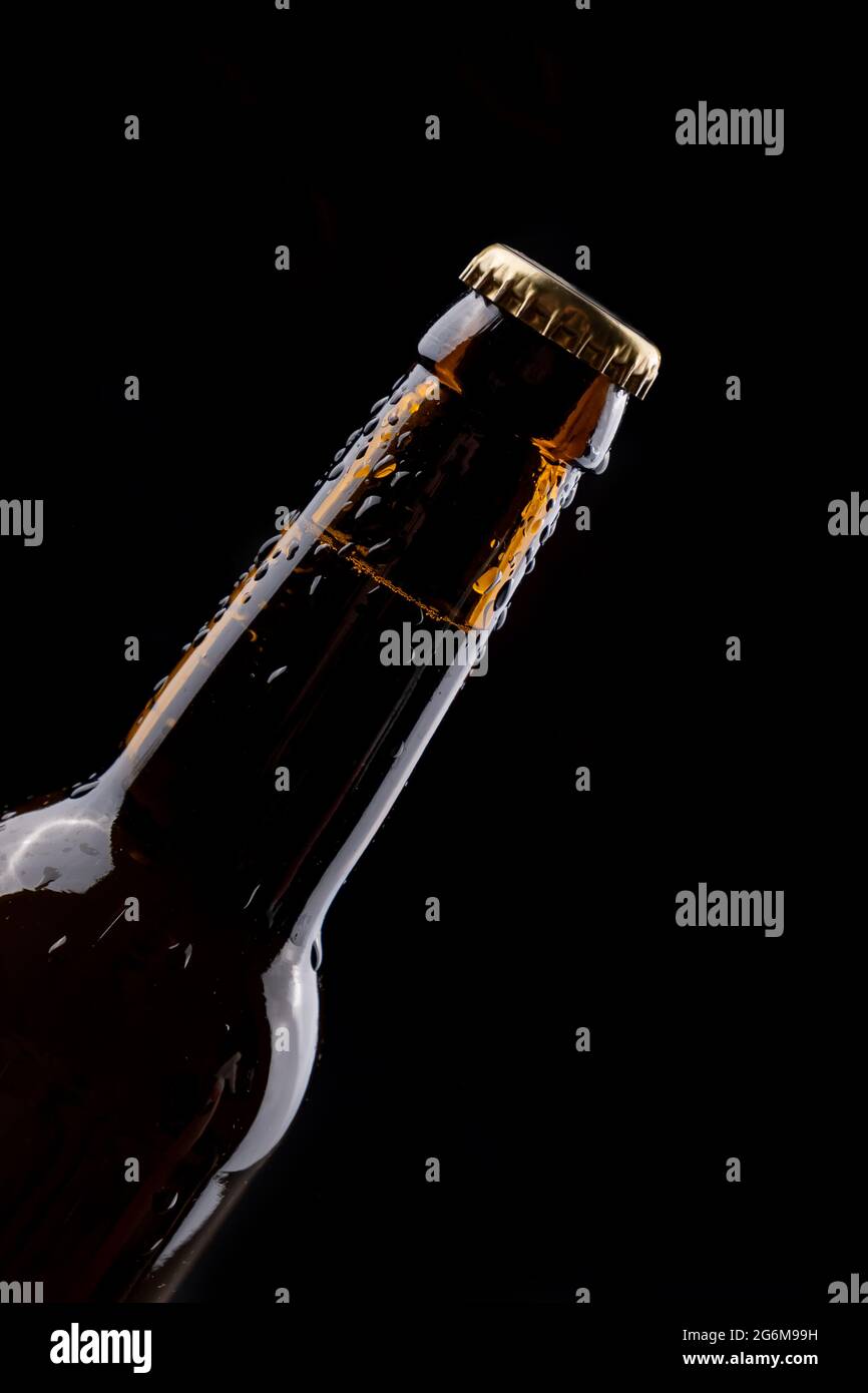Dark glass beer bottle with condensation drops on black background