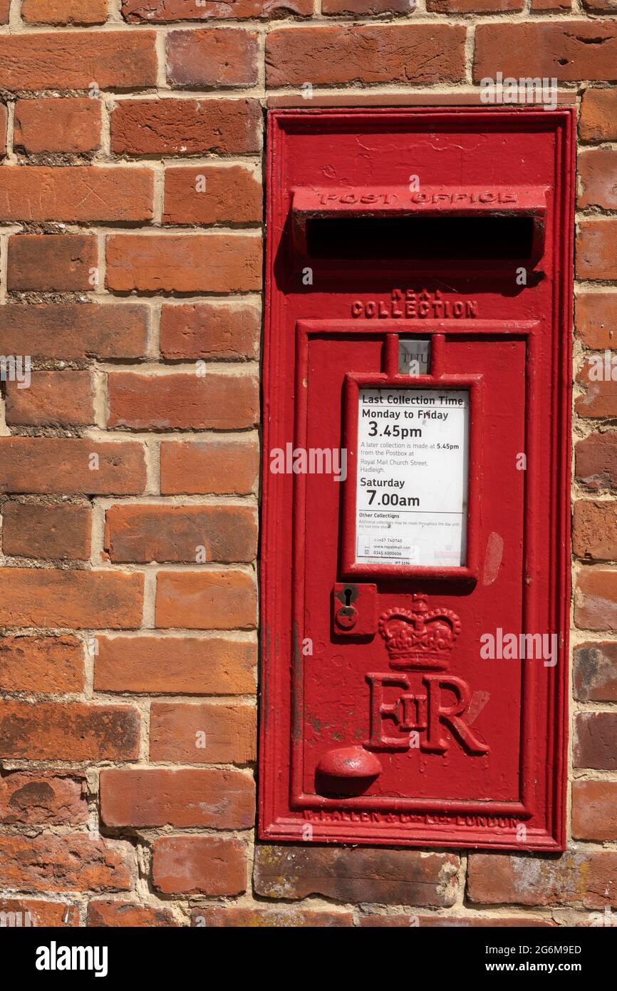 Traditional red letter box built into a red brick wall showing collection times England Stock Photo