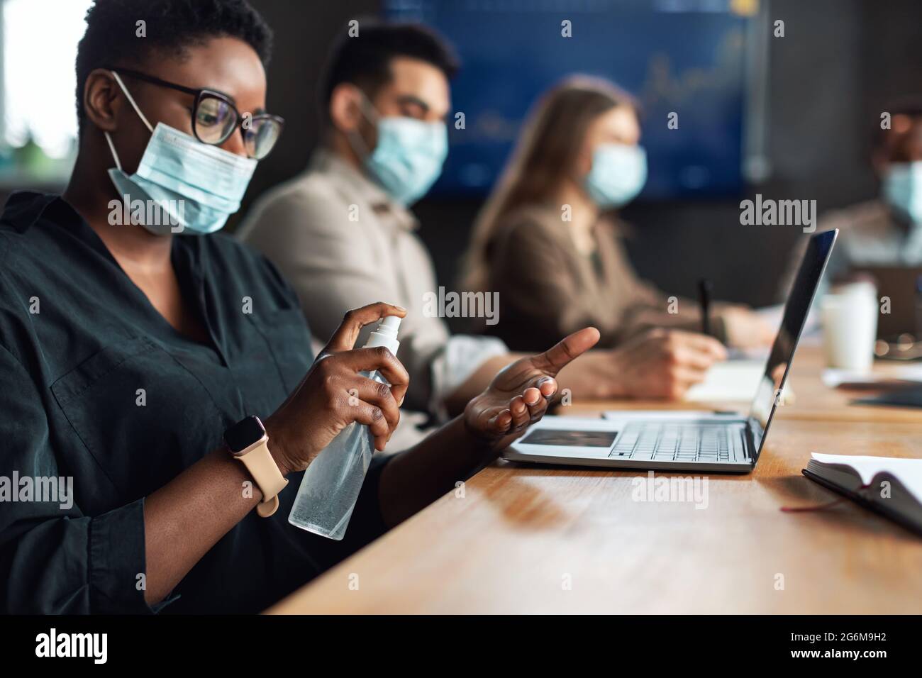 Multicultural workers wearing medical masks, black woman using ...
