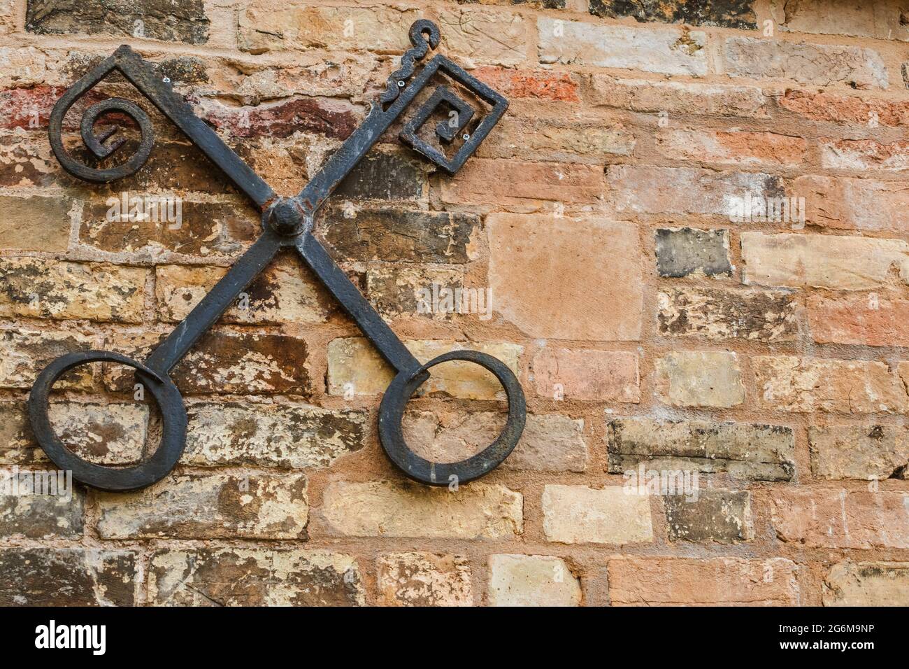 Iron cross keys on old brick wall at Peterhouse  Cambridge. Keys of Heaven refers to the image of crossed keys used in ecclesiastical heraldry, Stock Photo