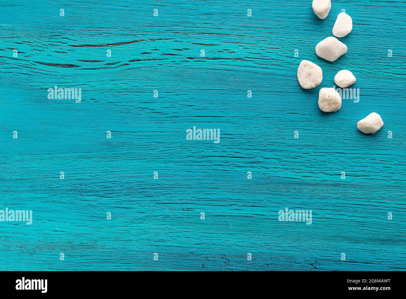 Abstract grungy blue wooden background with white stones. Copy-space, place for text. Flat lay, top view. Stock Photo