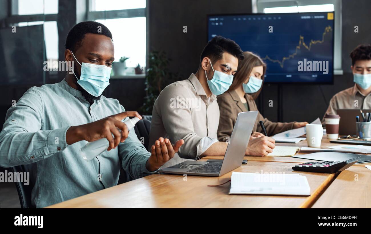 Multicultural workers wearing medical masks, black man using ...