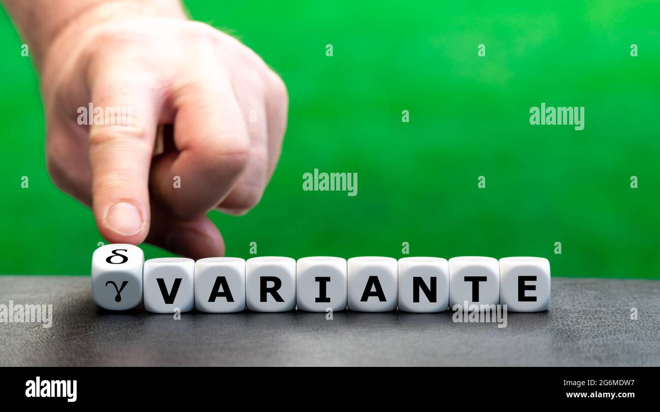 Hand turns dice and changes the German expression 'gamma variante' (gamma variant) to 'delta variante' (delta variant). Stock Photo