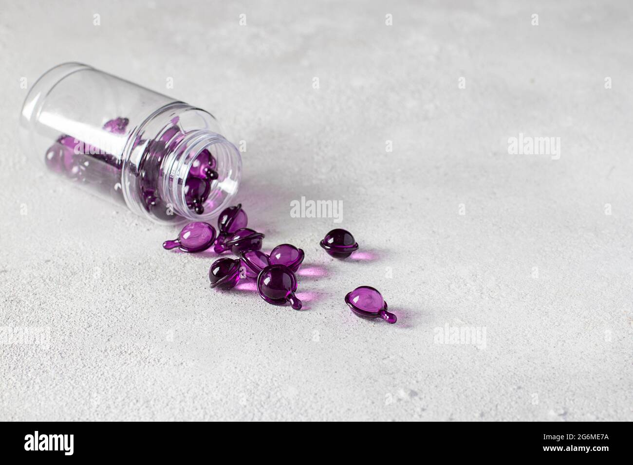 Hair Vitamin Capsules Pour Out of the Bottle on a Gray Background: Hair Treatment and Care Products With Oil for Damaged, Highlighted, Permed and Colo Stock Photo