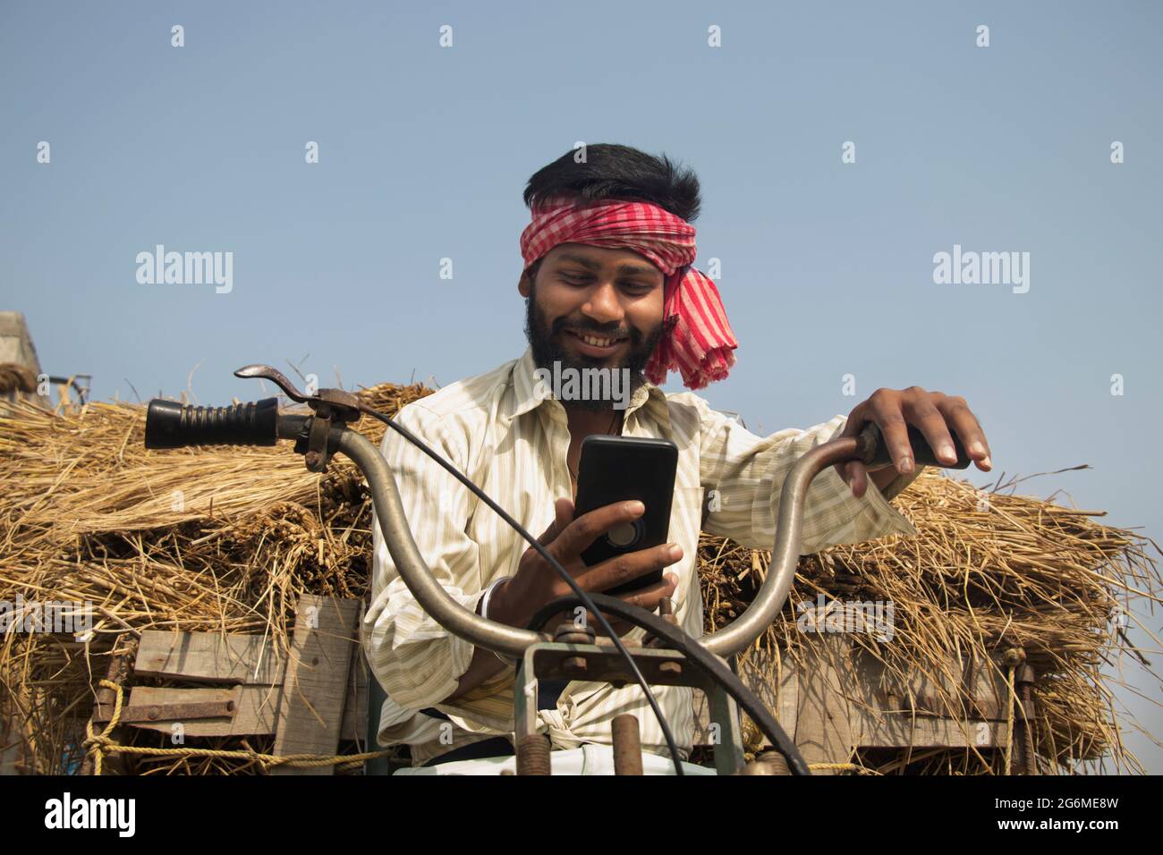 Young Adult man driving machine rickshaw and using smartphone Stock Photo