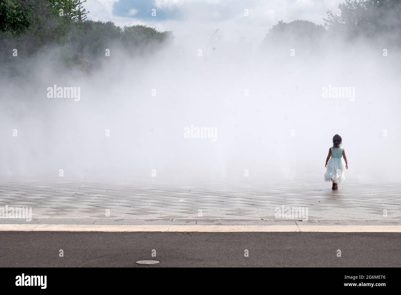 A young unattended girl enters the Fountain of the Fairs in Flushing Meadows Corona Park in Queens, New York City. Stock Photo