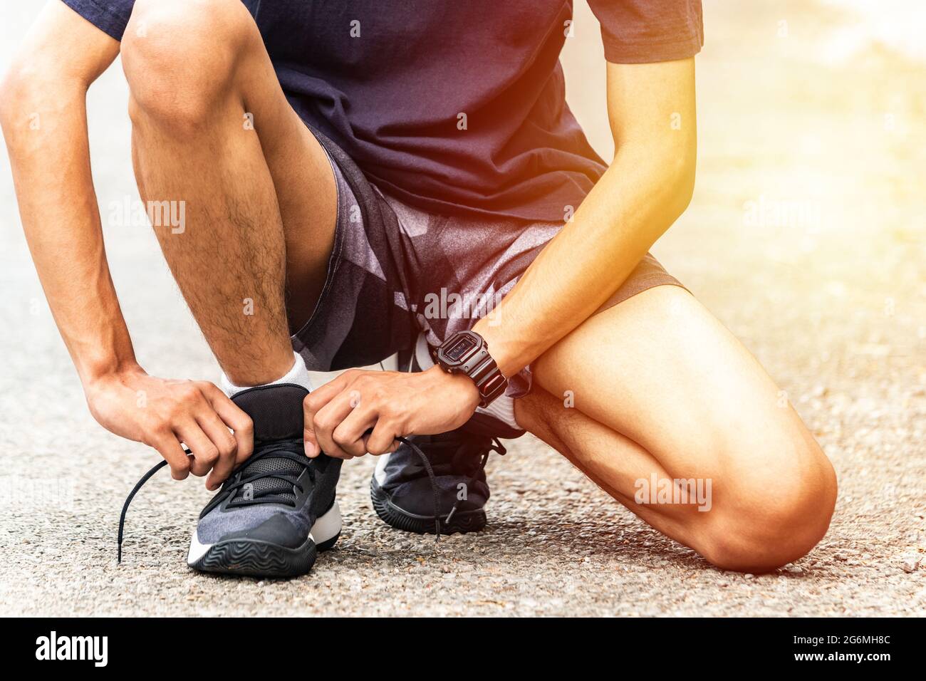 Runners are tying their shoelaces, He running in the park. Close-up man tying jogging shoes. Stock Photo