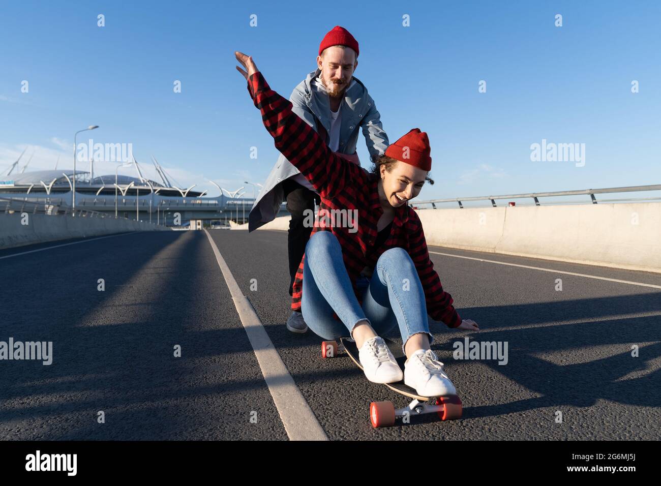 Stylish man and woman skating on longboard enjoy time together. Urban fashion and trendy activity Stock Photo