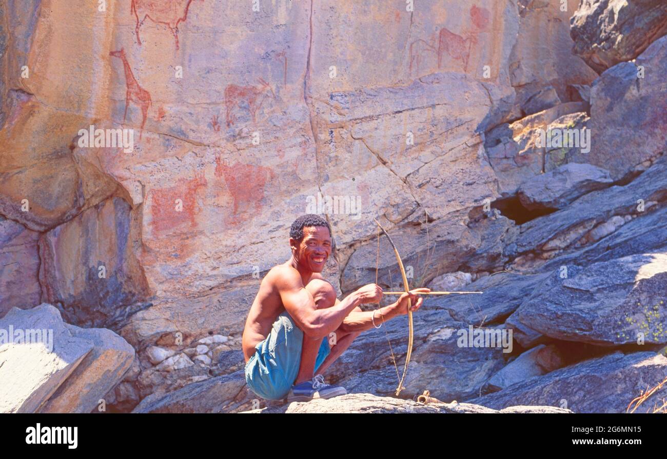 Botswana: A bushmen hunter in front of the ancient stone paintings in the Tsodillo Hills in the Central Kalahari Stock Photo