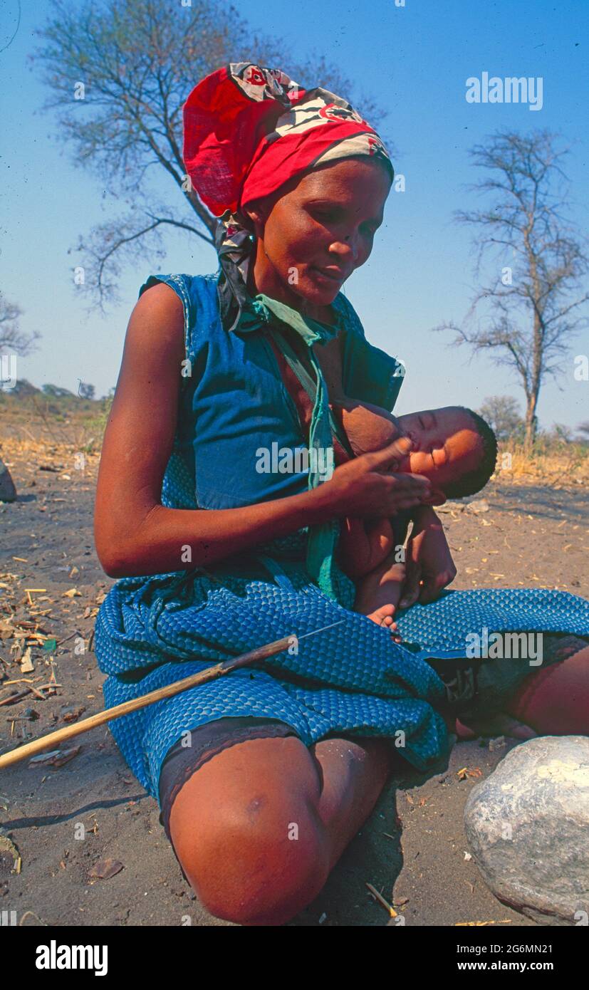 Botswana: A san woman with her baby creating bushmen art out of oostrich eggs at Tsodillo Hills in the  Okavango Delta within the Central Kalahari Stock Photo