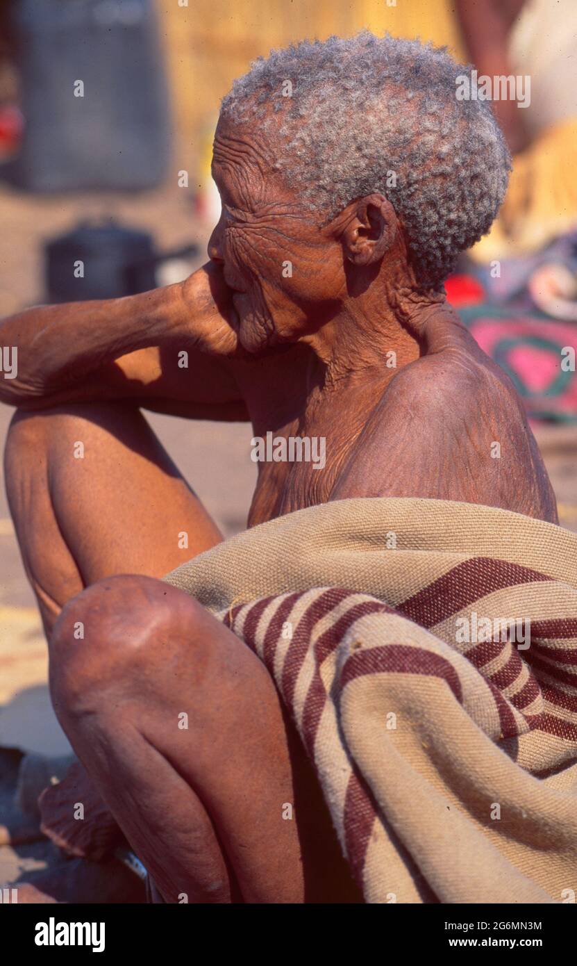 Botswana: A old san woman sitting in the desert of the central Kalahari near the holy Tsodillo Hills Stock Photo