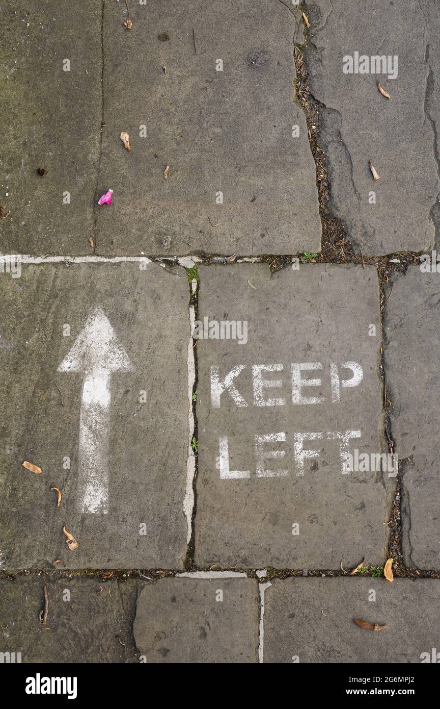 KEEP LEFT social distancing sign painted on the pavement (sidewalk). Stock Photo