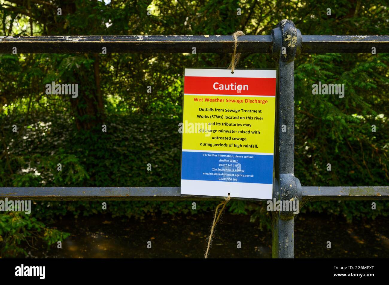 Wet weather sewage discharge warning notice attached to metal railings. Stock Photo