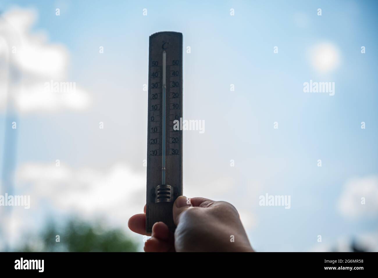 Wooden thermometer in a woman's hand. Extreme hot weather. Stock Photo