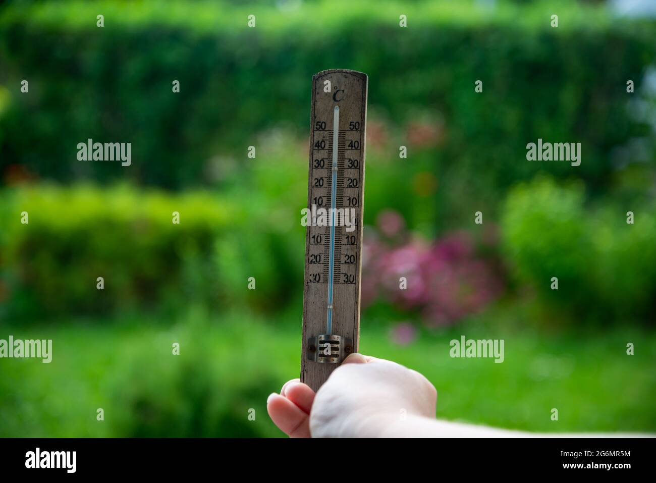 Wooden thermometer in a woman's hand. Extreme hot weather. Stock Photo