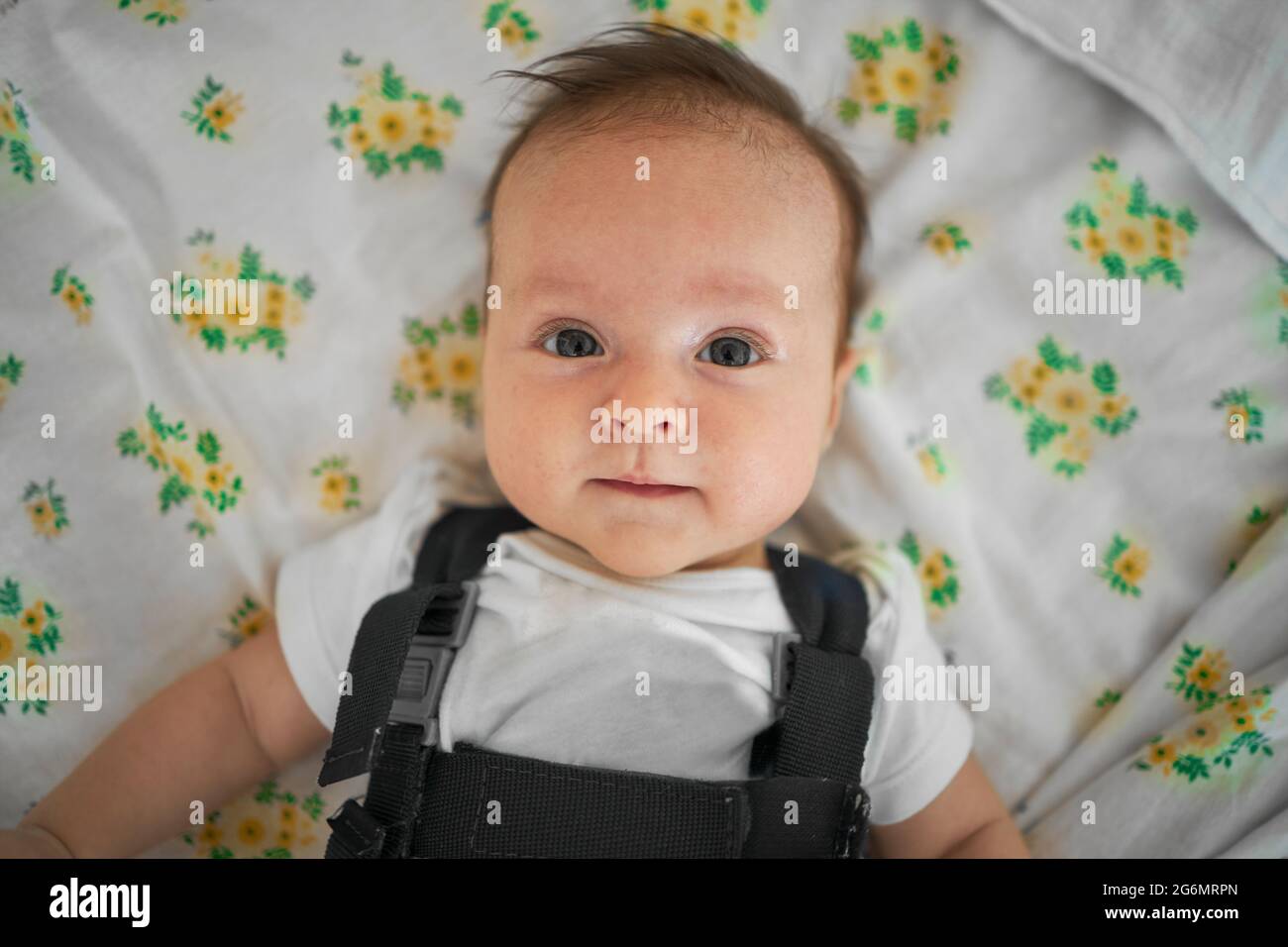 Cheerful baby laying in bed with clean sheets Stock Photo