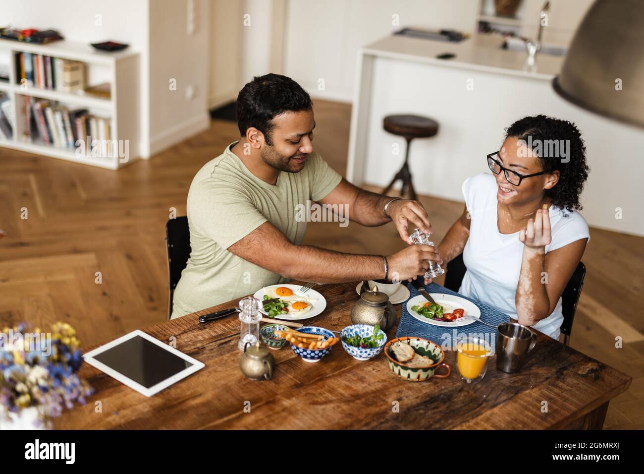 Middle eastern man and woman smiling while having breakfast in kitchen at home Stock Photo