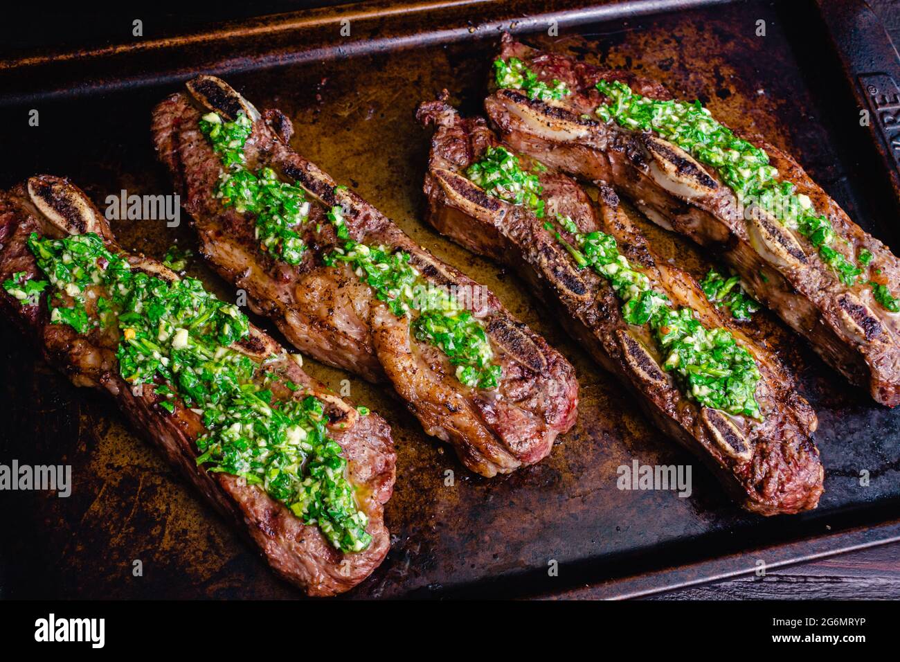 Argentinean-Style Grilled Short Ribs With Chimichurri: Barbecued flanken beef ribs topped with chimichurri sauce Stock Photo