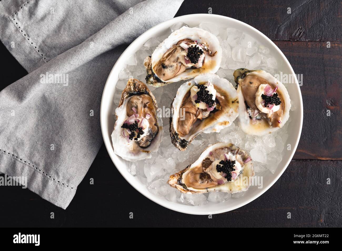 Dirty Oysters Served in a Bowl of Crushed Ice: Raw oysters topped with caviar, minced shallot, and creme fraiche Stock Photo