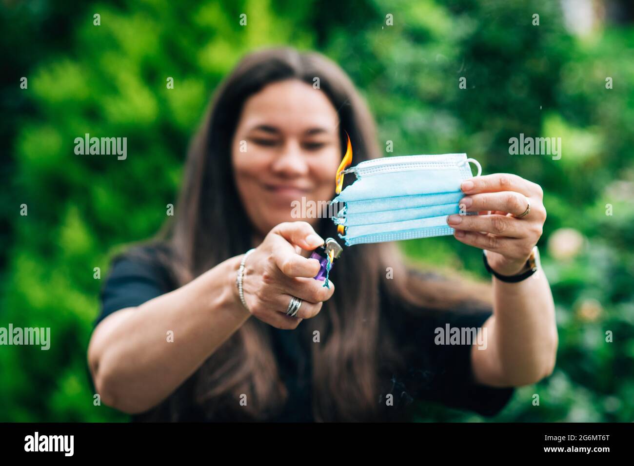a woman burning setting fire to a facemask to signal the end of the covid 19 coronavirus restrictions and freedom day on the 19th July in England. Stock Photo