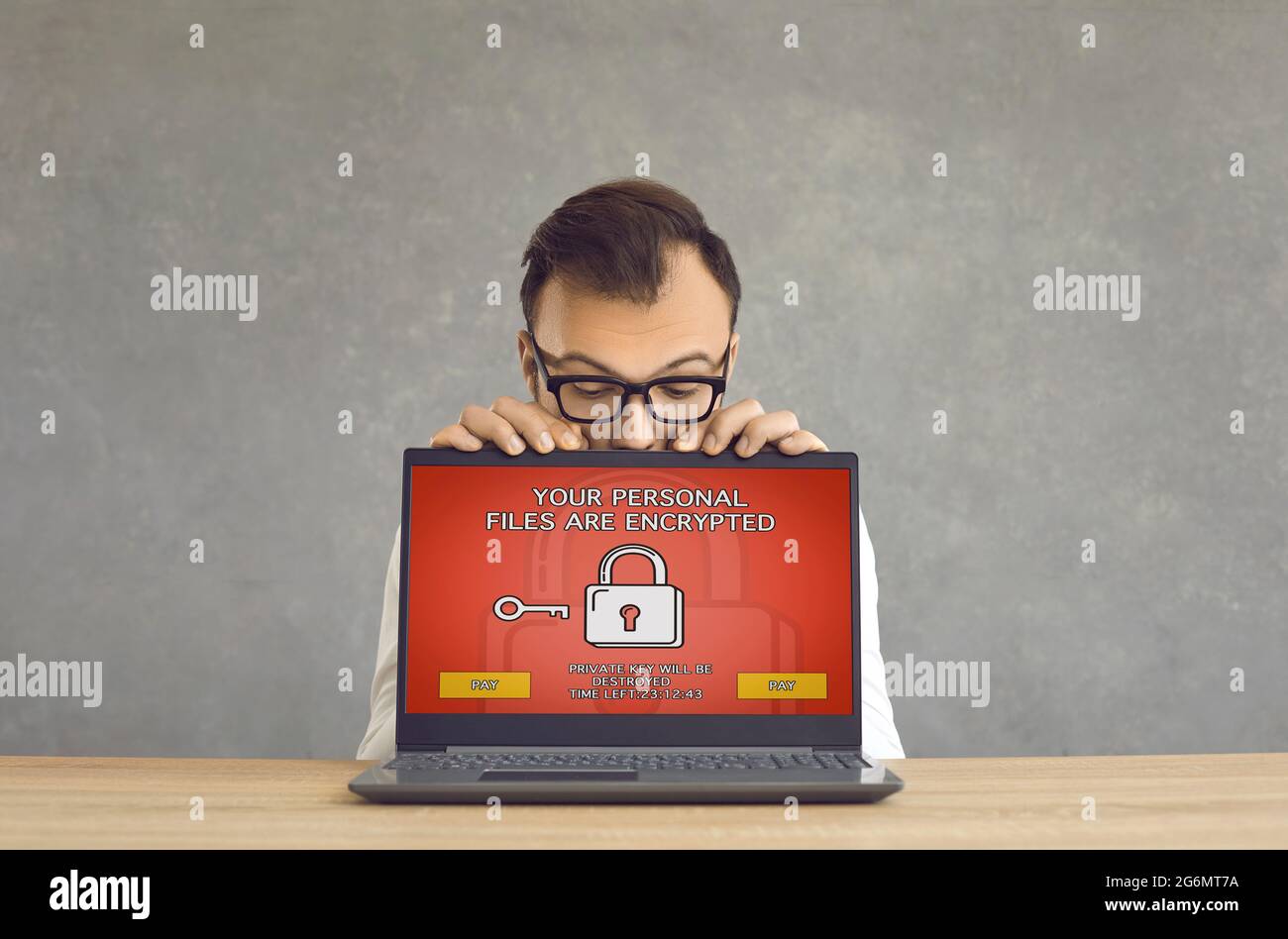 Man gets his laptop computer hacked and receives a ransomware warning on the screen Stock Photo