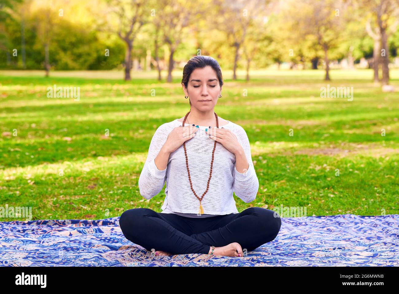Latin woman performing Reiki poses in a park. Yoga meditation. Stock Photo