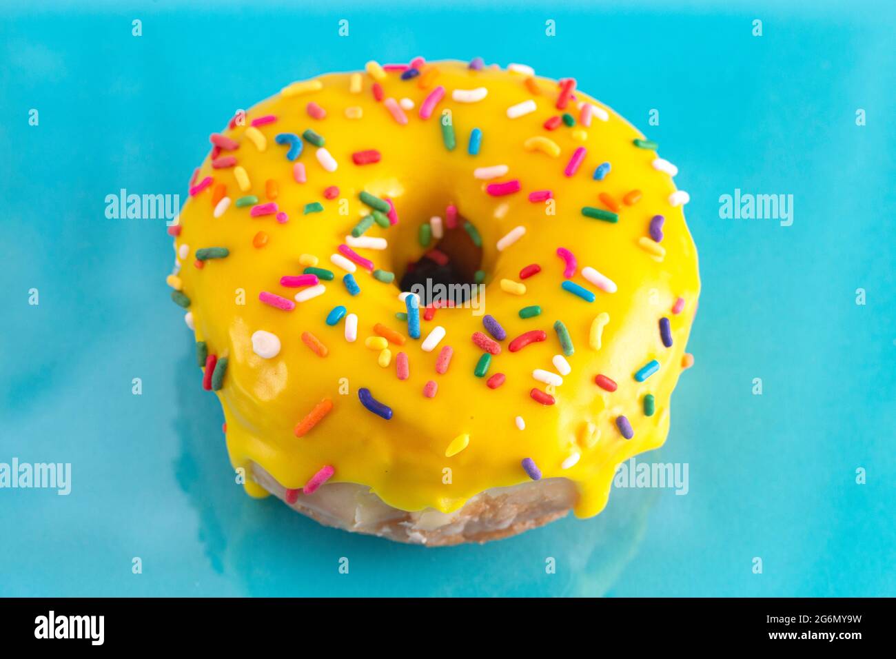 A Yellow Sprinkle Donut on a Blue Background Stock Photo Alamy