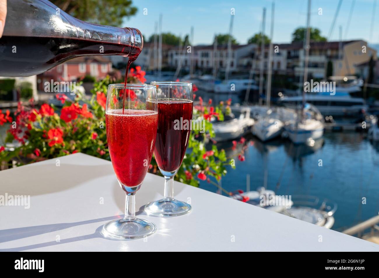 Summer party with kir royal cocktail, pouring of French brut champagne sparkling wine and creme cassis in glasses in yacht harbour of Port Grimaud nea Stock Photo