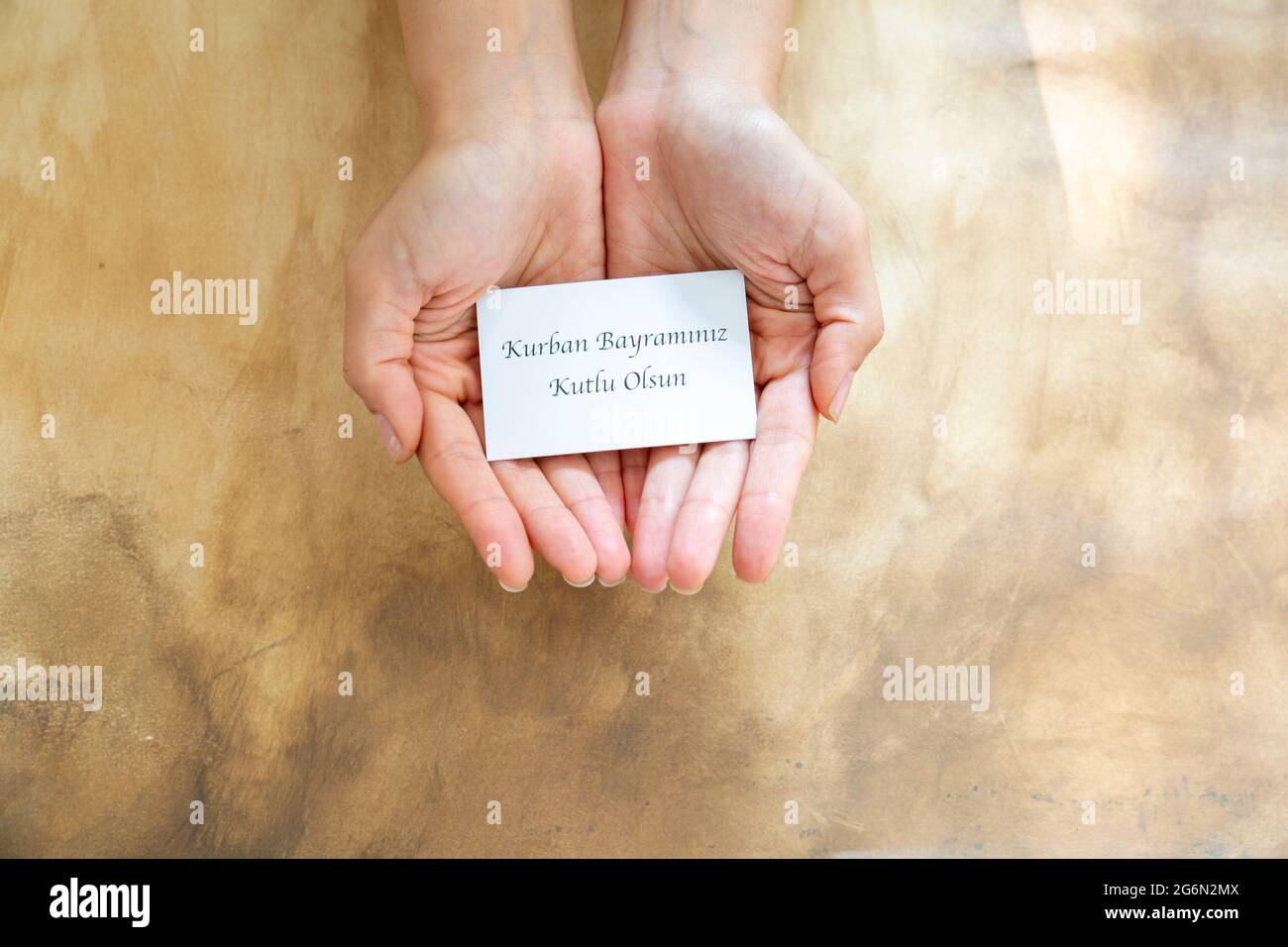 Hand holding Eid-al-Adha card ( 'Happy feast of sacrifice' on the card written in Turkish writers,) Stock Photo