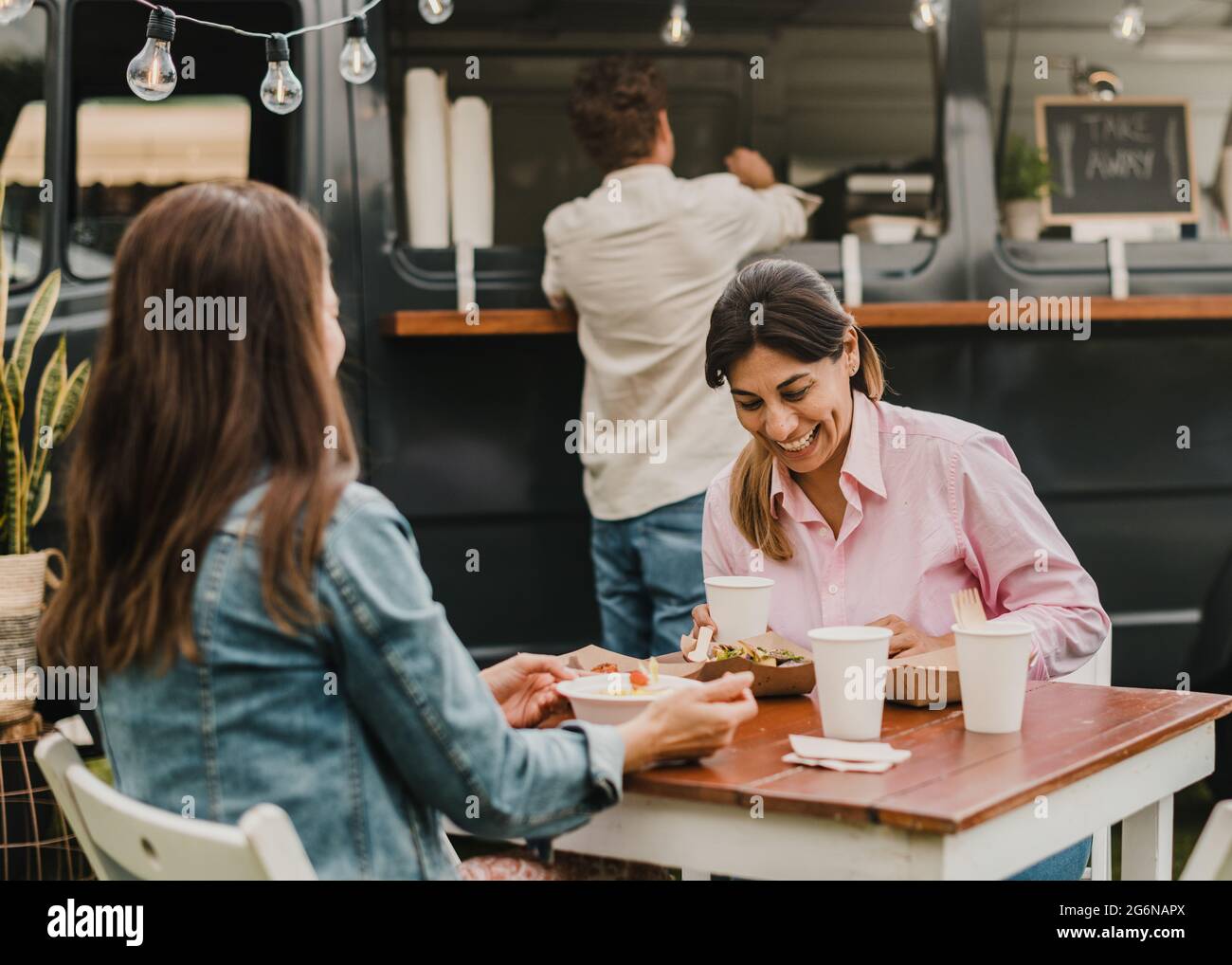 Mature women having fun eating at food truck outdoor - Focus on right face Stock Photo