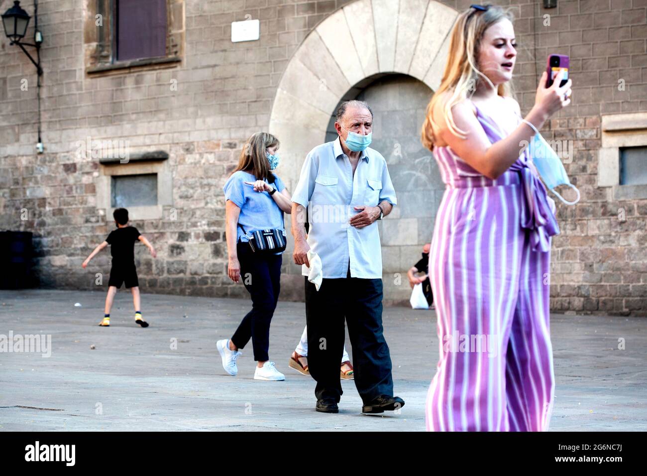 Local man walking past tourists, Barcelona, Spain. Stock Photo
