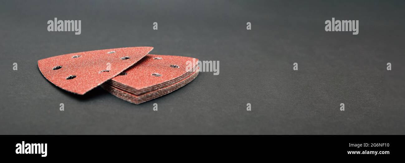 Sandpaper triangular shape, on a black background. For sanding wood and