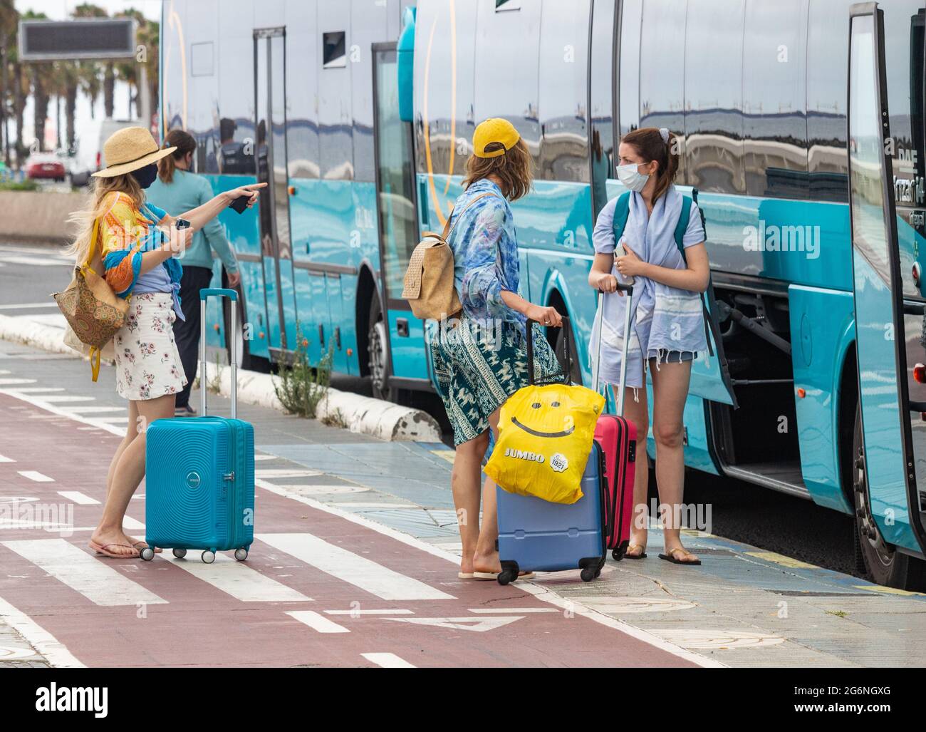 Las Palmas, Gran Canaria, Canary Islands, Spain. 7th July, 2021. Tourists  waiting for airport bus near the city beach in Las Palmas on Gran Canaria.  The Canary Islands, currently on the Amber