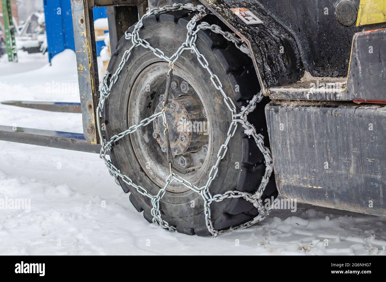 The loader is driving in the snow, the wheels are equipped with chains